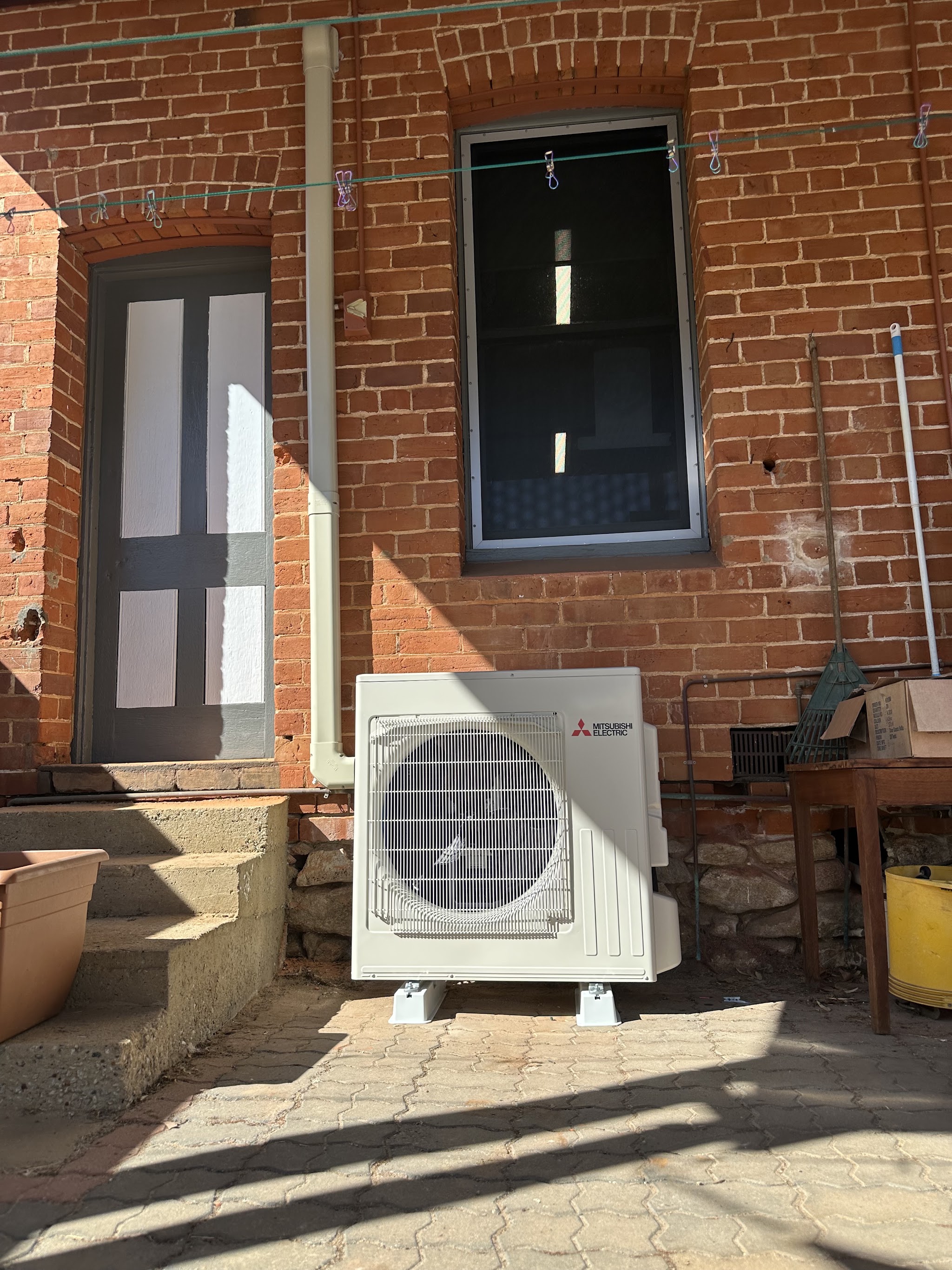 A Mitsubishi Electric outdoor unit installed against an old red brick building